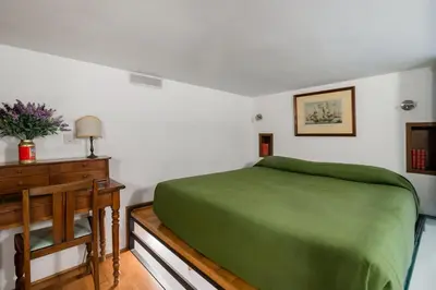 a bedroom with a green bed and a wooden dresser at Trastevere Cottage in Rome