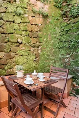 a wooden table with two chairs and a stone wall at Trastevere Cottage in Rome