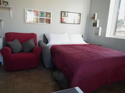 a bedroom with a bed and a red chair at WelcRome Appartamento Roma Centro in Rome