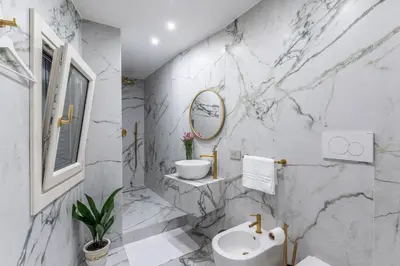 a white marble bathroom with a sink and a mirror at Vista su Campo de Fiori in Rome