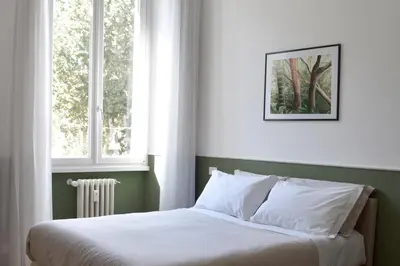 a bedroom with a bed with white sheets and two windows at RoMa Apt In Vatican in Rome