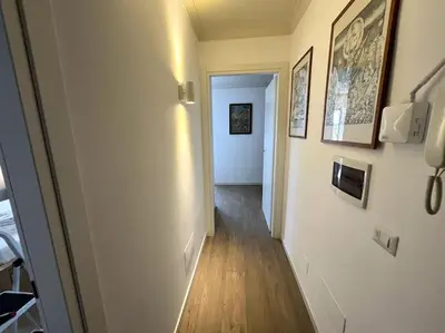 a hallway with a white wall with pictures on it at Trastevere Penthouse in Rome