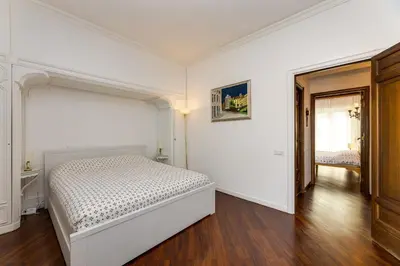a white bedroom with a bed and a hallway at Elegante appartamento 130mq in stile classico in Rome