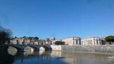 a bridge over a river in a city with buildings at Terrace & 1930s Charm - Vatican Walk in Rome