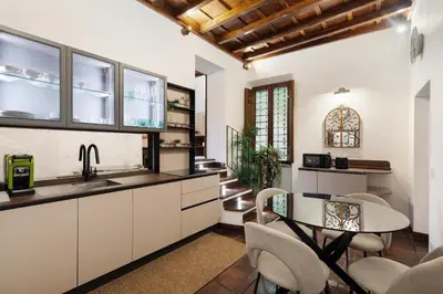 a kitchen with white cabinets and a table and chairs at Domus Minelli Navona by GHOR in Rome