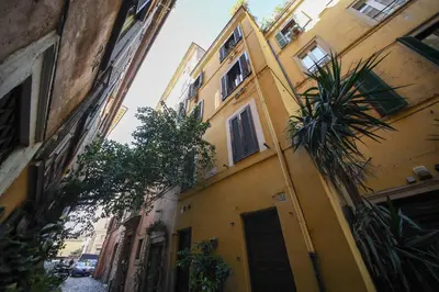 a yellow building with a palm tree in front of it at Domus Minelli Navona by GHOR in Rome