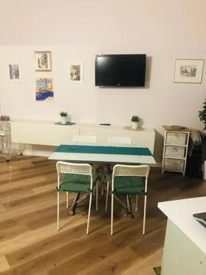 a room with a table with chairs and a flat screen tv at Charme Holidays Trastevere in Rome