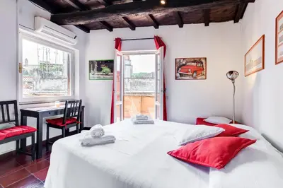 a bedroom with a large white bed with red pillows at Romantic house with terrace in Rome