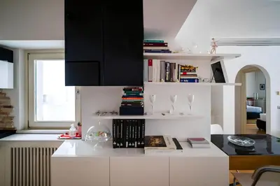 a kitchen with white cabinets and a book shelf at 5 Min From Trastevere Rome Chic Apartment in Rome