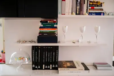 a shelf with books and wine glasses and books at 5 Min From Trastevere Rome Chic Apartment in Rome