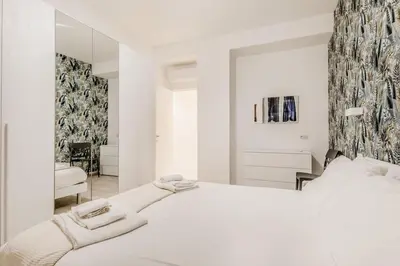 a white bedroom with a large bed and a mirror at Casa Vaticano di Simone&Alessio in Rome