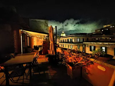 a patio with a table and chairs and a building at night at Casa di Alice in Rome