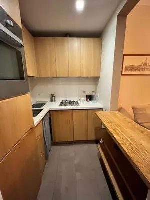 a small kitchen with wooden cabinets and a counter at Colosseum Apartment - Your Cozy Roman Escape in Rome