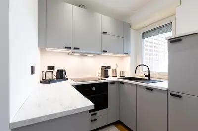 a kitchen with white cabinets and black appliances at Una Terrazza su San Pietro in Rome