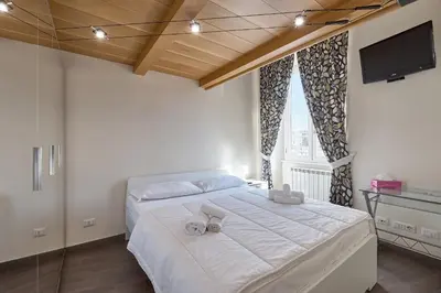 a bedroom with a large white bed with a flat screen tv at A casa di Roberta in Rome