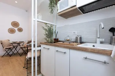 a kitchen with white cabinets and a table in the background at La Maison du Charme in Rome