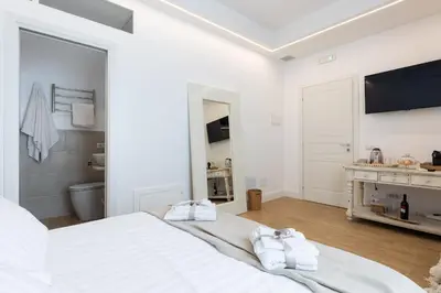 a white bedroom with a large bed with two towels at La Maison du Charme in Rome