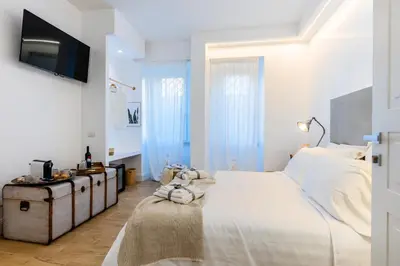 a white bedroom with a bed and a tv at La Maison du Charme in Rome