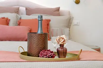 a tray with a champagne bottle and a glass on a bed at Romance al Colosseo 3 in Rome