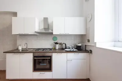 a white kitchen with white cabinets and a sink at Elegant loft at Piazza Vittorio in Rome