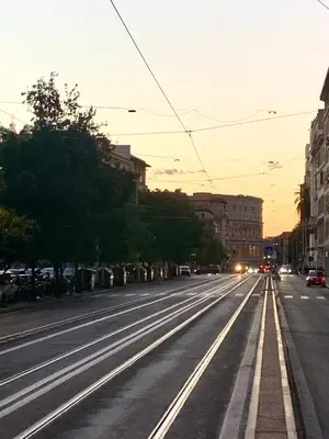 an empty street at sunset with cars driving down it at A due passi dal Colosseo in Rome