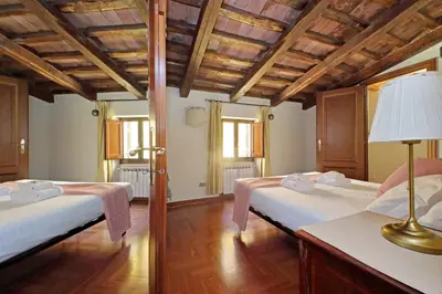 two beds in a room with wooden ceilings at Classic roman home next to Popolo Square in Rome