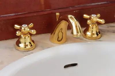 a sink with two gold faucets on top of it at Classic roman home next to Popolo Square in Rome