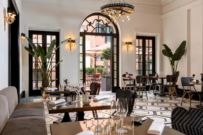 a restaurant with tables and chairs and a chandelier at Rocco Forte Hotel De La Ville in Rome