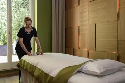 a woman standing next to a bed in a room at Rocco Forte Hotel De La Ville in Rome