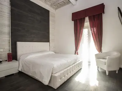 a bedroom with a white bed and a chair at Royal Rooms in Rome