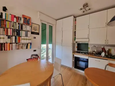 a kitchen with white cabinets and a wooden table at Incantevole bilocale a Città Giardino in Rome