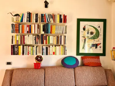 a couch in a living room with a book shelf with books at Incantevole bilocale a Città Giardino in Rome