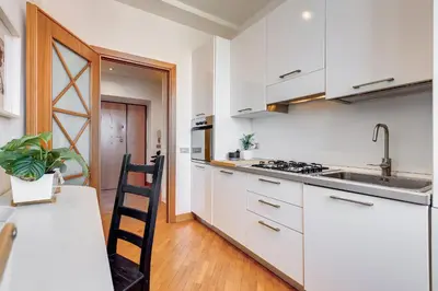 a kitchen with white cabinets and a sink and a table at Romaviva Luxury Attic Apartment - San Giovanni in Laterano - Metro A C - Central Rome in Rome