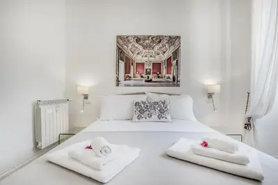 a bedroom with a white bed with towels on it at Roma Vatican Suites Inn in Rome