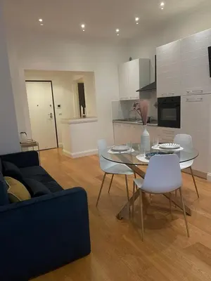 a living room with a table and white chairs at Forte's Apartment in Rome