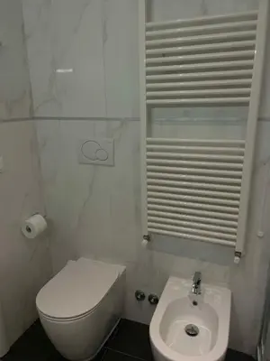 a white bathroom with a toilet and a sink at Forte's Apartment in Rome