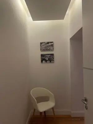 a white chair in a room with a ceiling at Forte's Apartment in Rome