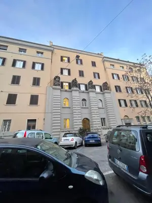 a parking lot with cars parked in front of a building at Forte's Apartment in Rome
