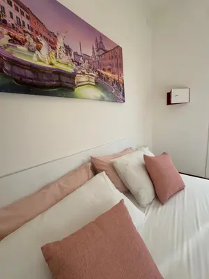 a white bed with pillows and a painting on the wall at Vacanze Romane Apartment in Rome in Rome