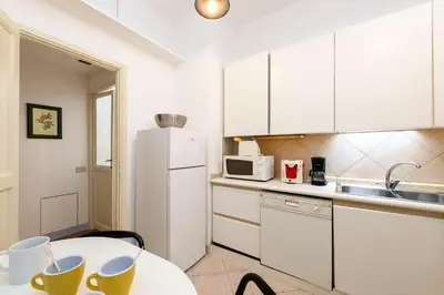 a kitchen with a table and a white refrigerator at Cartari Deluxe Apartment in Rome