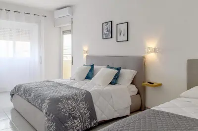 a white bedroom with a large bed with blue pillows at Veroli Vacanze Romane in Rome