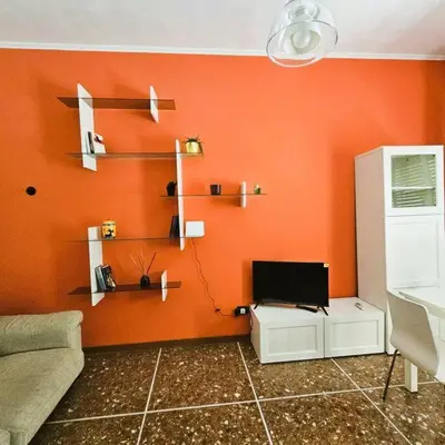 a living room with an orange wall with shelves at La casetta di Laura in Rome