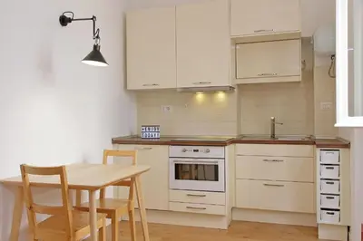 a kitchen with white cabinets and a table with chairs at Caprareccia In Monti by Halldis in Rome