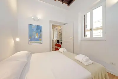 a white bedroom with a large bed with two towels on it at Caprareccia In Monti by Halldis in Rome