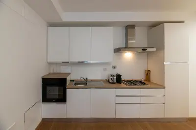 a kitchen with white cabinets and a stove top oven at Piazza Lodi - Apartment in Rome