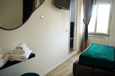 a room with a bed and a mirror and towels at XCross Suites Basilica San Paolo in Rome