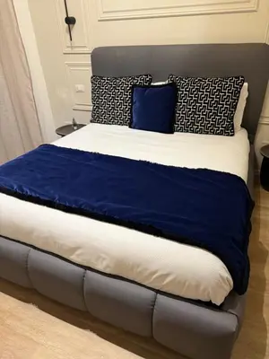 a large bed with blue and white sheets and pillows at XCross Suites Basilica San Paolo in Rome