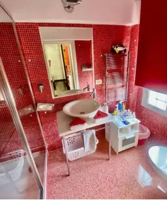 a red bathroom with a sink and a mirror at Ave Roma Suite in Rome