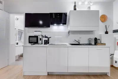 a white kitchen with white cabinets and a microwave at Colosseum Charming Suite monti district with jacuzzi in Rome