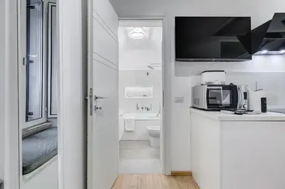 a white bathroom with a tv and a microwave at Colosseum Charming Suite monti district with jacuzzi in Rome